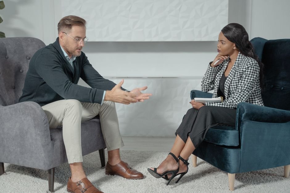 Two people talking in armchairs in a bright room